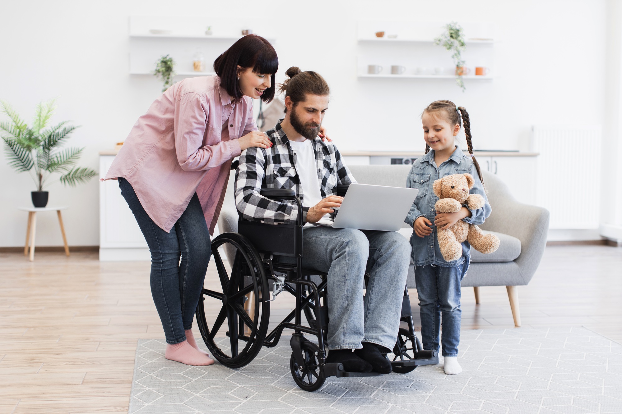 Family together in modern kitchen supporting father with disability